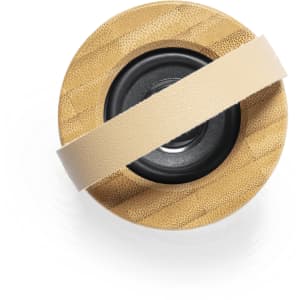 A round speaker in natural bamboo finish with a beige strap across the middle. It features a black speaker cone.