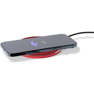 A wireless charger in red with a smartphone placed on top, displaying a charging indicator.