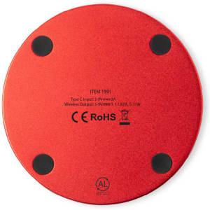 A round, red wireless charger with a smooth surface and four rubber feet on the base.