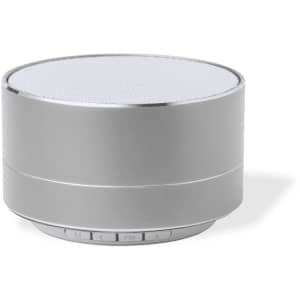 A round silver speaker with a metal mesh top and control buttons on the base. It features a simple, sleek design.