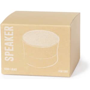 A brown cardboard box containing a black speaker, featuring a simple logo and product illustration.
