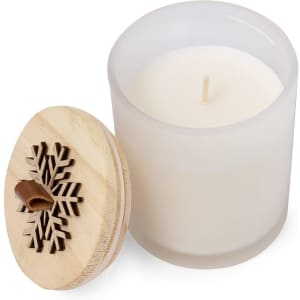 A white aromatic candle in a frosted glass container, topped with a wooden lid featuring a snowflake design.
