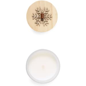 A white aromatic candle with a wooden snowflake lid. The candle is housed in a simple glass container.