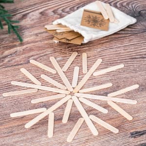 A collection of wooden sticks arranged in a circular pattern with a small pouch of cards nearby.