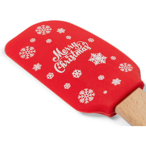 A red spatula featuring white snowflakes and the phrase "Merry Christmas." It has a wooden handle and a logo.