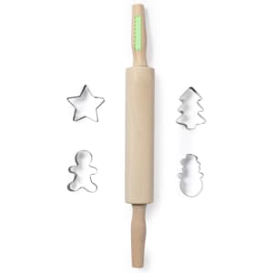 A wooden rolling pin with green detailing, accompanied by star, tree, gingerbread man, and snowman cookie cutters.