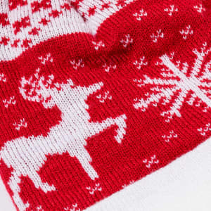 A red and white beanie featuring a festive reindeer and snowflake pattern, with a textured knit design.