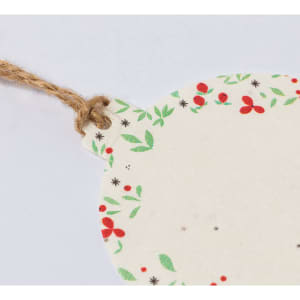 A round, cream-coloured tag with a floral red and green border, attached to a twine string.