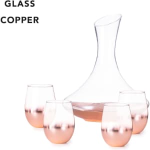 A glass decanter with a curved shape and four copper-hued stemless glasses.
