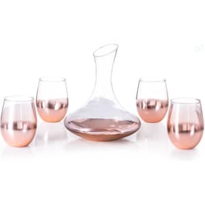 A glass decanter in a curved shape with four matching rose gold-stemmed glasses.