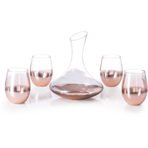A glass decanter with a sleek design, accompanied by four rose gold-hued stemless wine glasses.