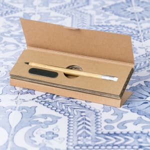 A grey-lead pencil nestled in a cardboard case, resting on a decorative blue patterned surface.