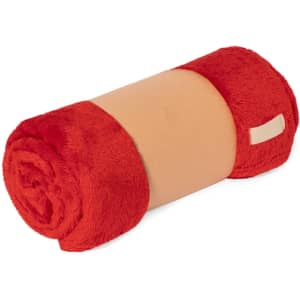 A rolled red and beige blanket with a soft texture and a tag, featuring a logo.