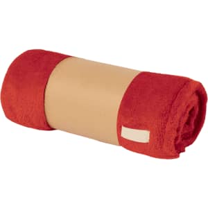 A rolled, soft red blanket with a beige band around it, featuring a small branding label.