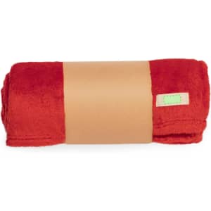 A red plush blanket neatly rolled and secured with a beige band, featuring a small logo tag.