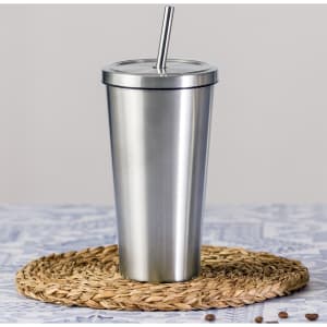 A drink bottle in silver stainless steel with a straw and a lid, placed on a woven mat.
