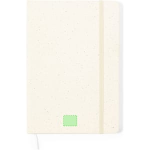 A notepad with a cream speckled cover, featuring a green logo and an elastic band closure.