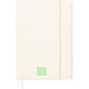 A notepad featuring a cream cover with speckled details, a green label, and a cream elastic band.