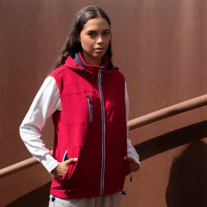A red vest with a hood, featuring zip pockets and contrasting white sleeves, displayed against a brown background.