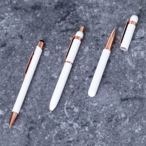 A set of four white pens with rose gold accents, including a stylus and a ballpoint pen, on a textured surface.