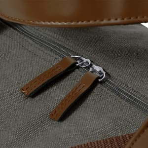 A close-up of the zipper details on a green fabric bag with brown leather accents. The bag features two zip pulls.