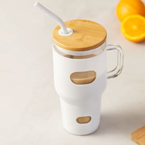 A drink bottle with a clear body, bamboo lid, and white silicone sleeve, featuring a straw.