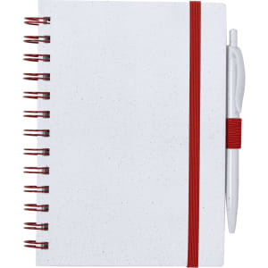 A white notebook with a red elastic band and a pen. It features spiral binding and a speckled design.
