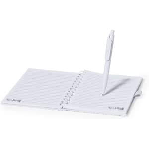 A white notebook with lined pages and a pen positioned on it. The notebook has a logo on the cover.