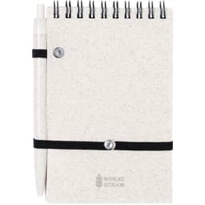 A cream-coloured notebook with a spiral binding and a pen attached, featuring a black elastic band and branding on the cover.