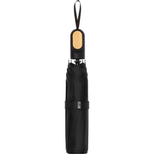 A black umbrella with a wooden handle, featuring a logo and secured with a strap.