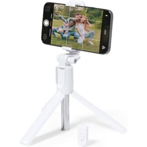 A white tripod holds a smartphone in landscape orientation, featuring a remote control for taking photos.