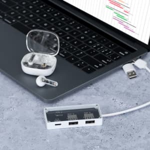 Webex earphones in a charging case, displayed beside a laptop and a USB hub, featuring a sleek white design.
