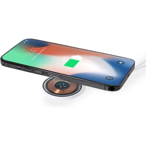 A wireless charger in silver with a sleek design and a smartphone charging on top.