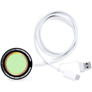 A round, black wireless charger with a green centre and a white USB-C cable attached.