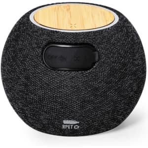 A round, dark grey speaker with a bamboo top and a small switch on the side. It features a logo on the bottom.