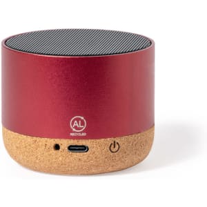 A red speaker with a cork base and a textured top surface, featuring a logo and connectivity port.