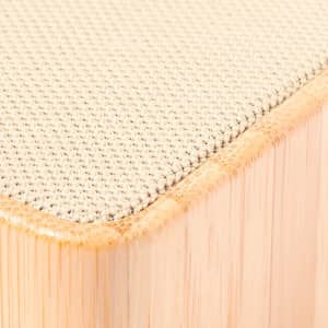 A close-up of a textured speaker with a soft beige fabric top and a wooden base.