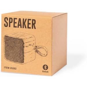 A brown cardboard box containing a Bluetooth speaker with a square shape and a carrying strap.