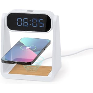 A white multifunction alarm clock with a digital display and a wireless charging pad for smartphones.