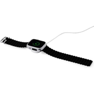 A smart watch with a square face and a black strap, connected to a charging cable. It features a logo on the front.