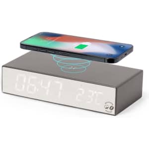 A multifunction alarm clock in grey with a wireless charging feature and a phone placed on top.