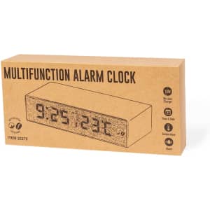 A multifunction alarm clock in a cardboard box featuring a digital display for time and temperature.