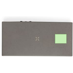 A grey multifunction alarm clock with a square logo and minimalistic design, featuring a wireless charging surface.
