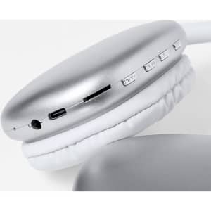 A pair of silver headphones with white cushioned ear pads, featuring buttons and a charging port.