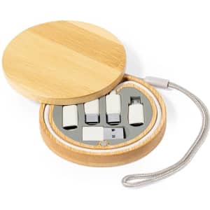 A bamboo container with a round lid holds a set of white charging cables and adapters.