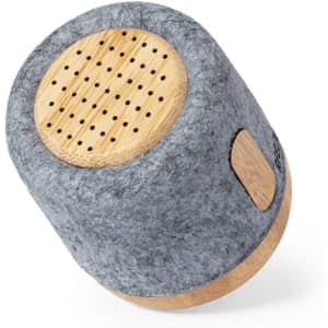A grey fabric speaker with a wooden base and a round shape, featuring holes for sound output and a logo.