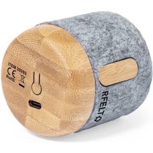A grey and wooden speaker featuring a felt exterior and a round design, with a logo on the side.