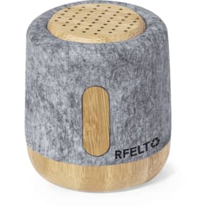 A grey and wooden speaker with a felt exterior and a circular top, featuring a branding logo on the side.