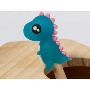 A teal dinosaur figure with pink spikes, placed atop a wooden surface. It has large, cartoonish eyes.