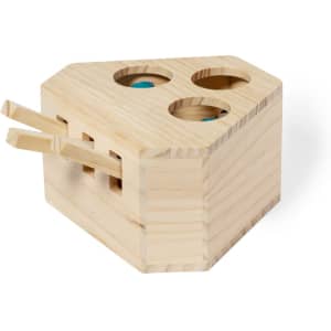 A wooden toy block with three holes and two wooden chopsticks, crafted from light-coloured timber.